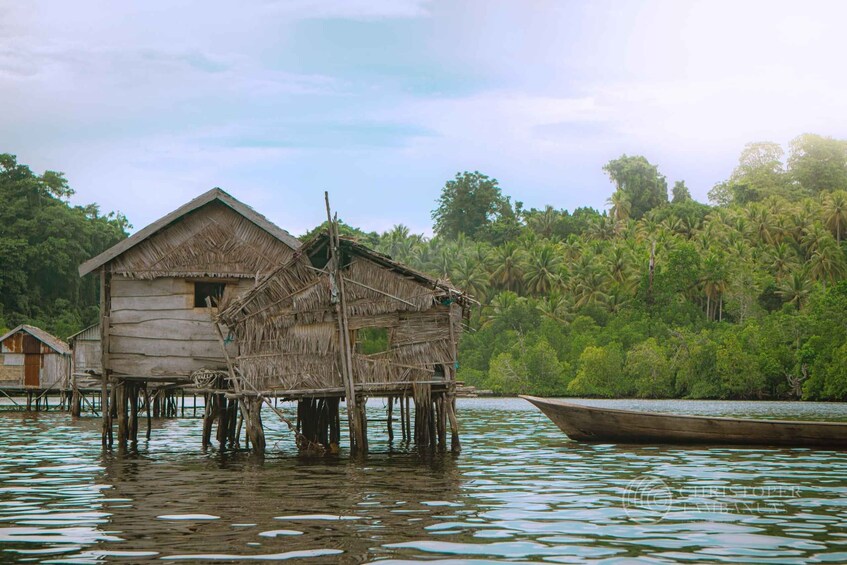 A traditional stilt house over water, surrounded by lush greenery and a calm river. 2