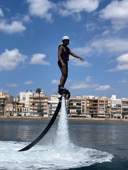 A person riding a jet ski, wearing a helmet, with a cityscape in the background. 4