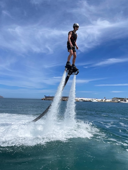 A person riding a jet ski over water with a clear sky and distant land in the background. 5