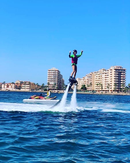 A person jet-skiing with water jets, a jet ski, and a coastal cityscape with buildings in the background. 2