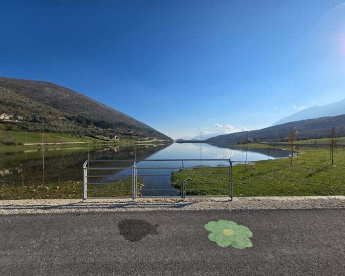 A lake with a metal gate, surrounded by hills and a clear sky. 2