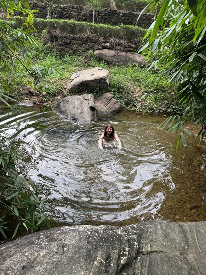 A person swimming in a natural water body surrounded by rocks and greenery. 3