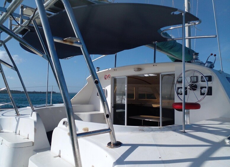 A sailboat's deck with a steering wheel, a table, and a covered area. 2