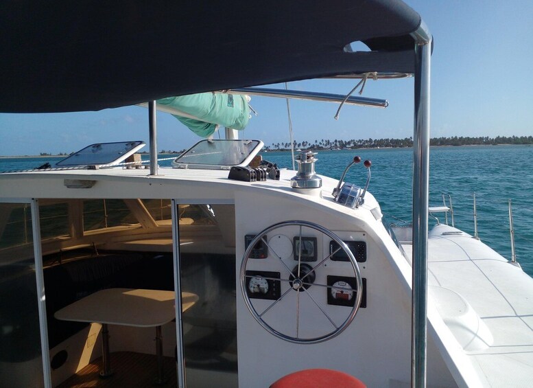 A boat's deck with a steering wheel, control panels, and a table under a canopy. 5