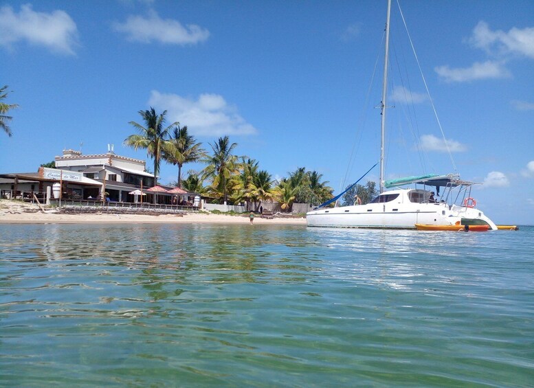 A white yacht docked near a beach with a building labeled 'Castelo do Mar' and palm trees. 3