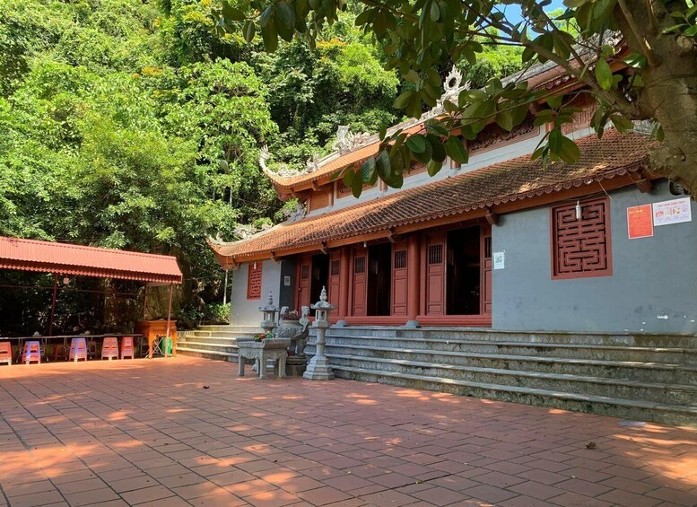 A traditional temple with a tiled roof, red doors, and a stone staircase leading up to the entrance. 5