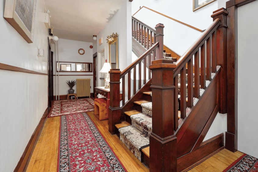 A wooden staircase with a patterned carpet leading to a landing. 2