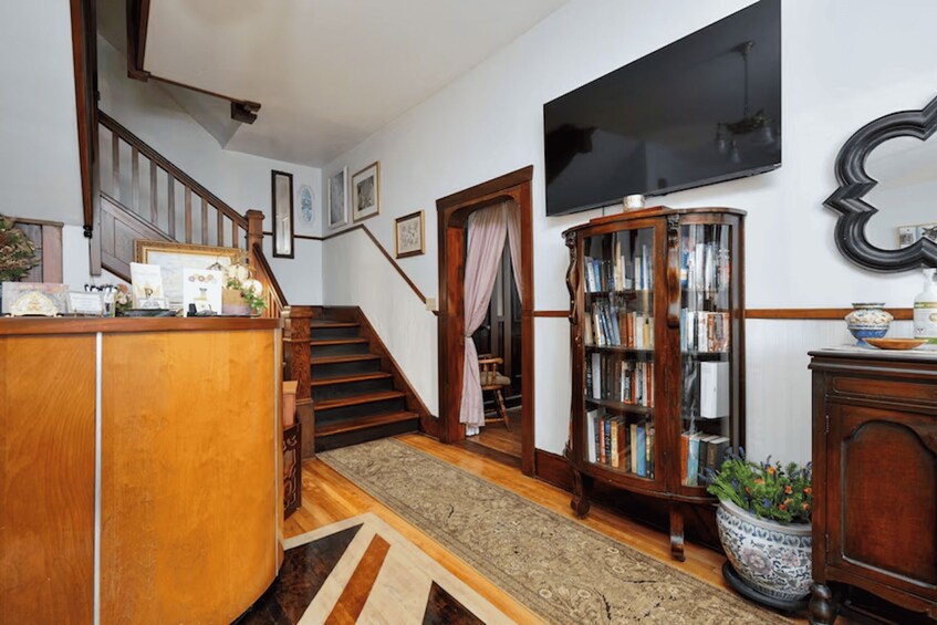 A wooden staircase, a bookshelf, a television, and a patterned rug in a home interior. 3