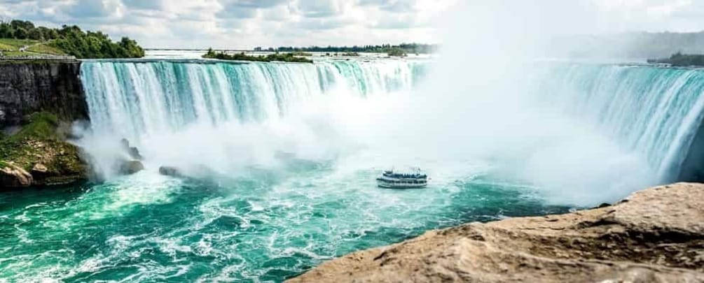 A large waterfall with a boat in the water. 1