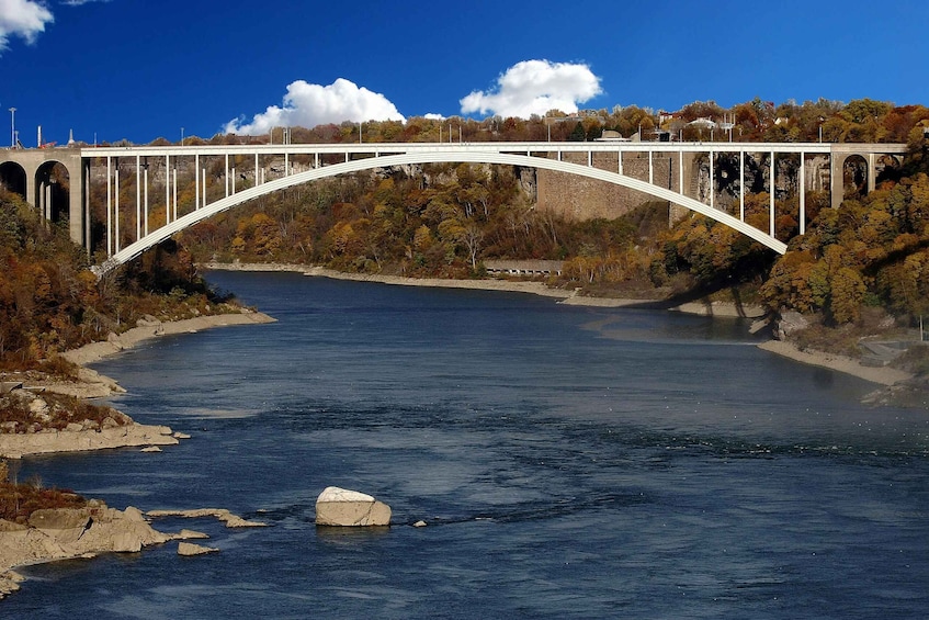 A white bridge over a river with autumn foliage and a clear sky. 2