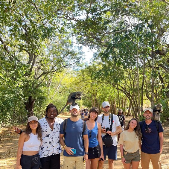 A group of people in a forested area with monkeys on their shoulders. 2