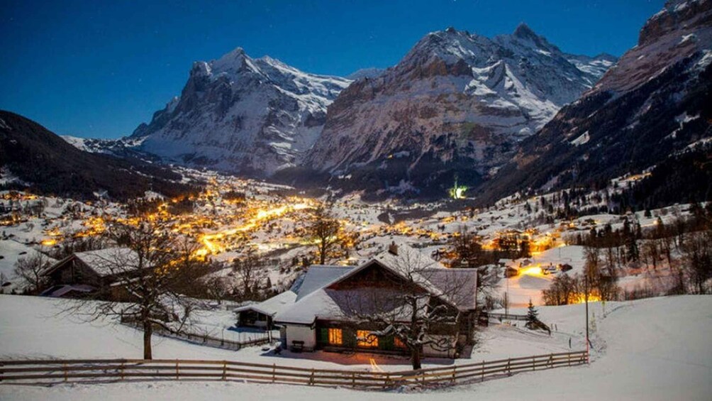 A snow-covered village with illuminated buildings and mountains in the background. 5