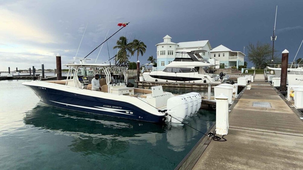 A marina with several boats docked, a large white building, and palm trees in the background. 3
