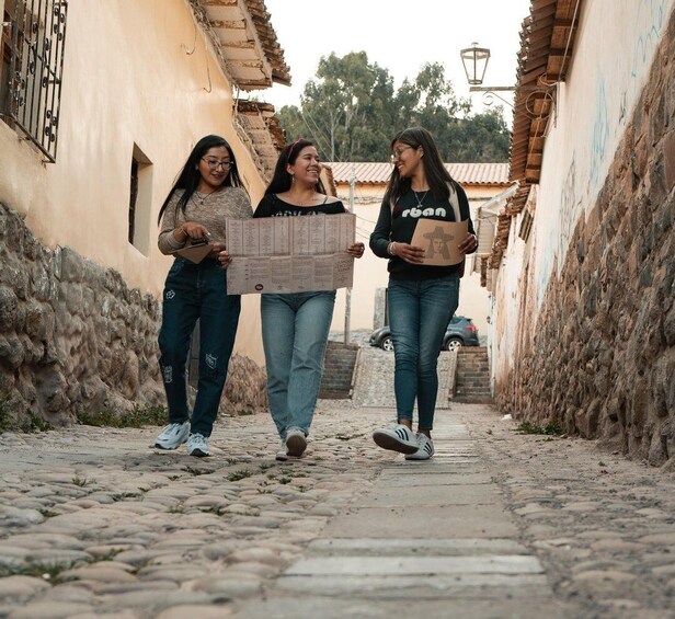 Three people walking down a cobblestone street in a narrow alleyway with buildings on either side. 2