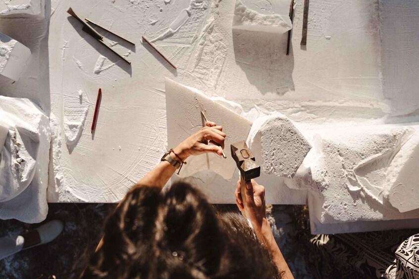 A person sculpting a white block with tools. 4