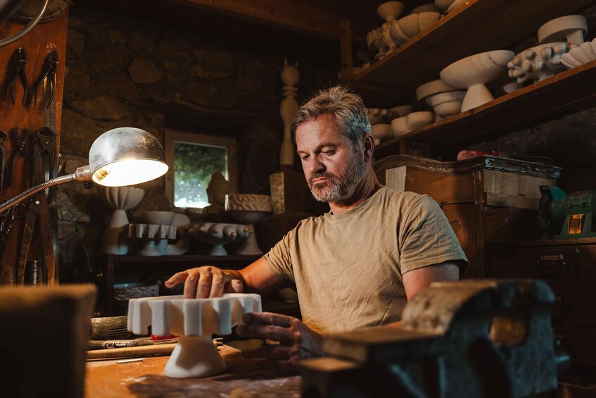 A person working with pottery in a workshop with shelves of pottery and tools. 5