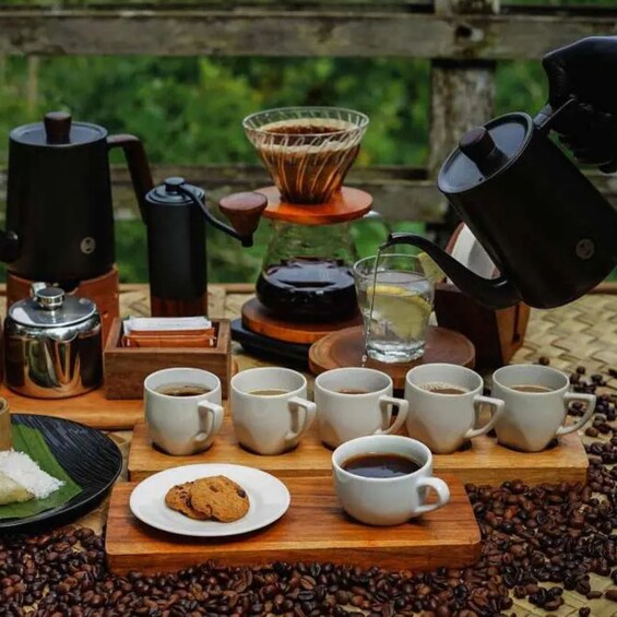 A coffee setup with multiple cups, a coffee press, and a plate with a cookie on a wooden table surrounded by coffee beans. 5