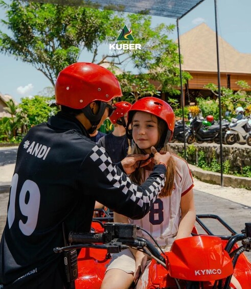 A person in a red helmet and black and white checkered jacket sitting on a red Kymco motorcycle. 4