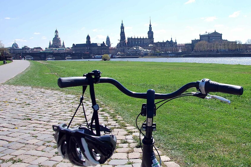 A bicycle parked on a cobblestone path with a river and historic buildings in the background. 4