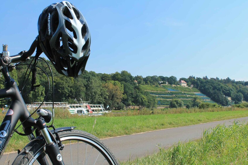A bicycle with a helmet, a river, and a boat in the background. 3