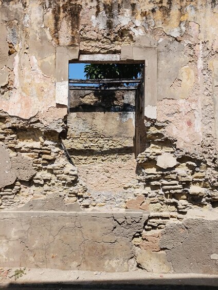 An ancient stone structure with a central doorway and surrounding ruins. 2