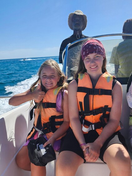 Two people on a boat wearing life jackets. 4