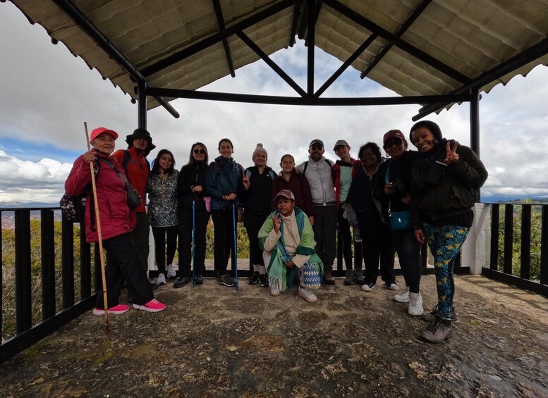 A group of people standing on a rocky platform under a shelter, with a mountainous landscape in the background. 5