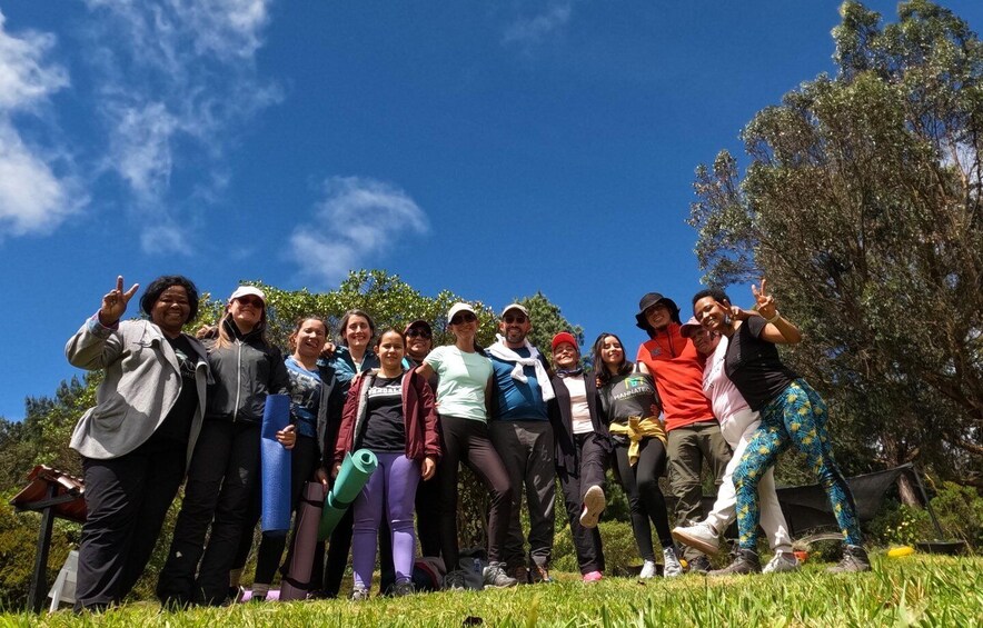 A group of people posing outdoors with trees and a clear sky in the background. 2