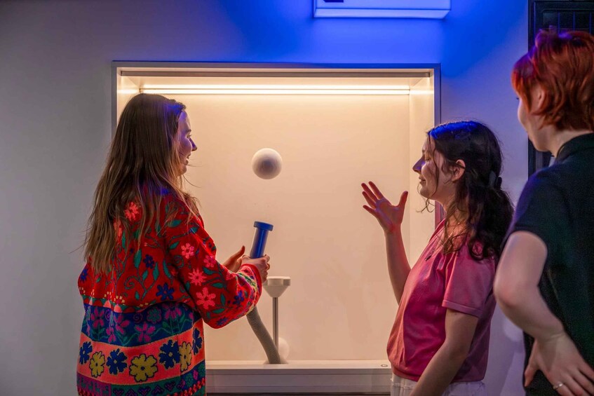 A person holding a blue object in front of a display case with a lighted interior. 2