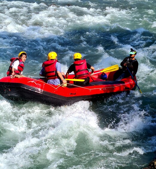 A group of people in a red inflatable raft navigating through turbulent waters. 5