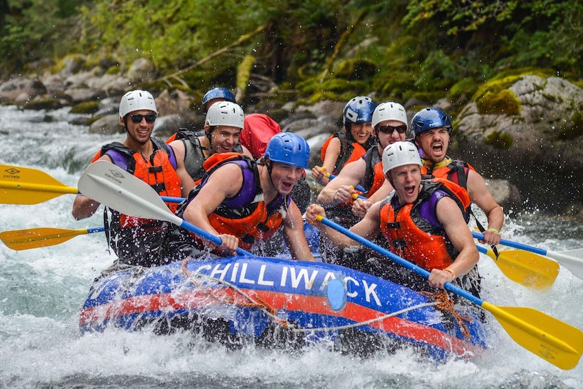 A group of people in a blue and red raft labeled 'CHILLWACK' navigating a river. 3