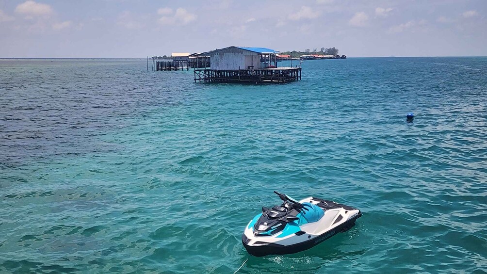 A clear blue sea with a jet ski in the foreground and a floating structure in the background. 3