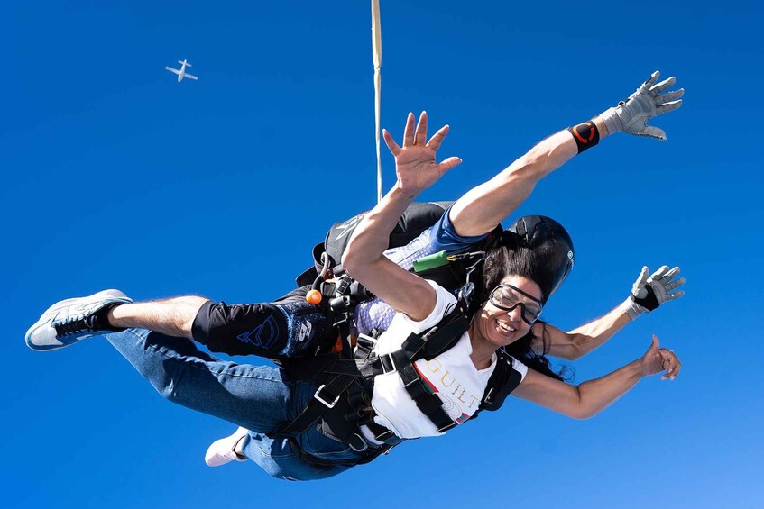 A person skydiving with outstretched arms, wearing a helmet and parachute gear. 2