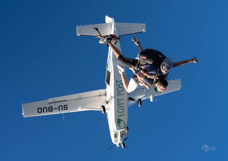 A person skydiving with a parachute, attached to a small aircraft labeled 'EGYPT POST'. 4