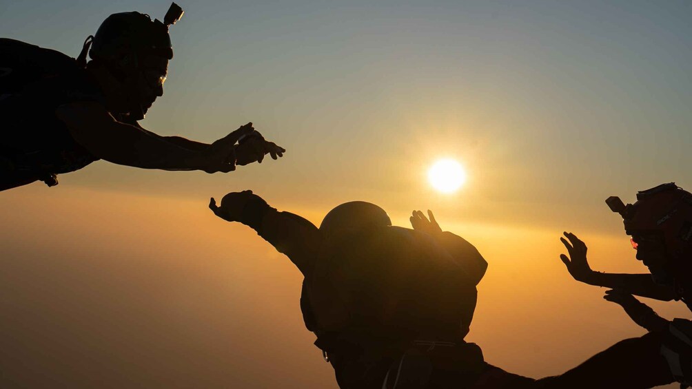 Silhouettes of people with raised arms against a sunset. 3