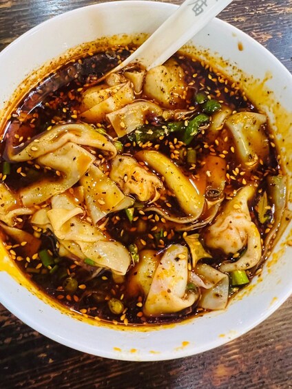 A bowl of soup with various ingredients and a spoon. 3