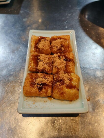 A white rectangular plate with six pieces of food topped with cinnamon. 5