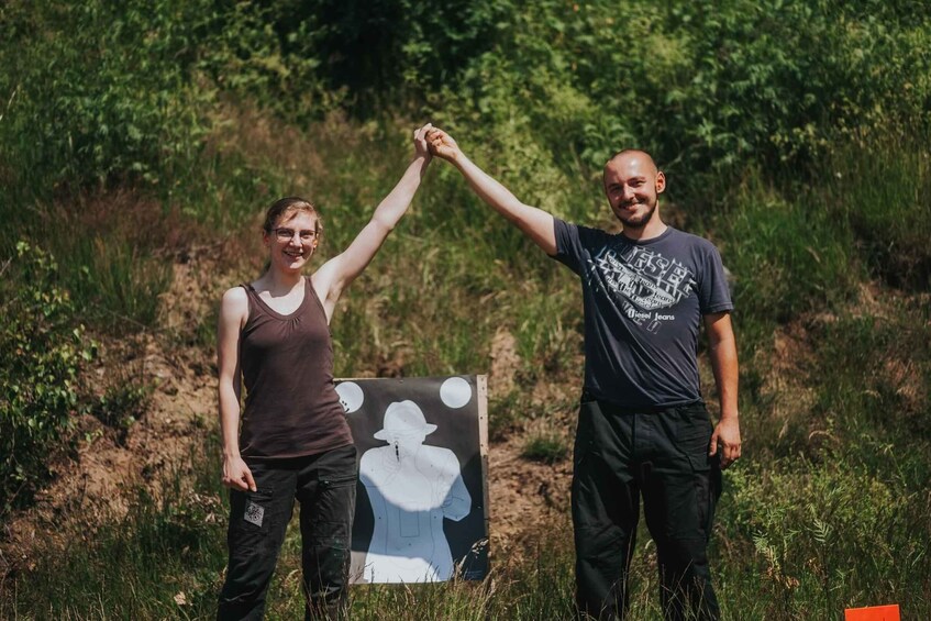Two people holding hands in a grassy outdoor area with a poster featuring a silhouette of a person. 1