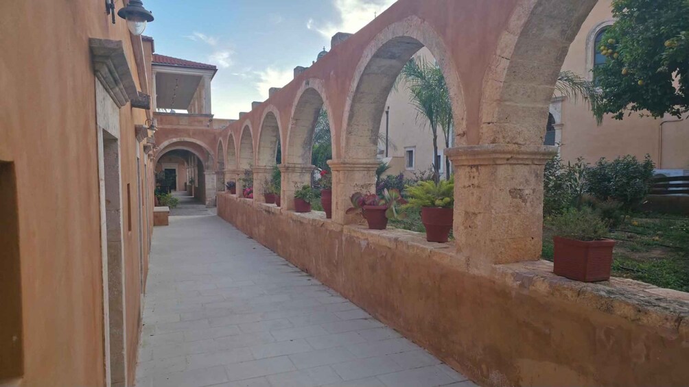 A corridor with arches, potted plants, and a clear sky. 3