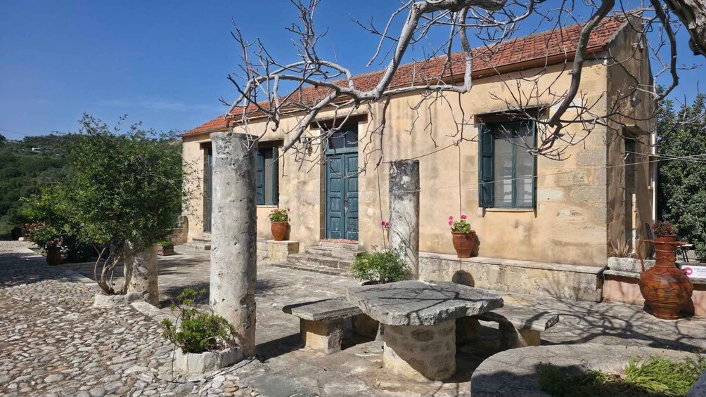 A stone building with a tiled roof, potted plants, and a stone bench. 2