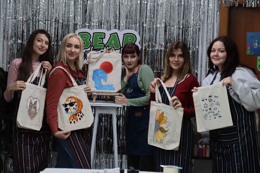 A group of people holding tote bags with various designs. 1