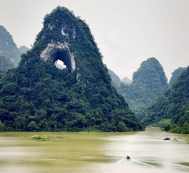 A river with a large rock formation and a boat. 1