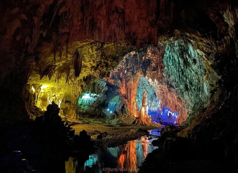 A cave illuminated with colorful lights reflecting on water. 5