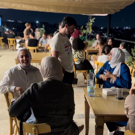 People seated at tables under an outdoor canopy, engaged in conversation. 3