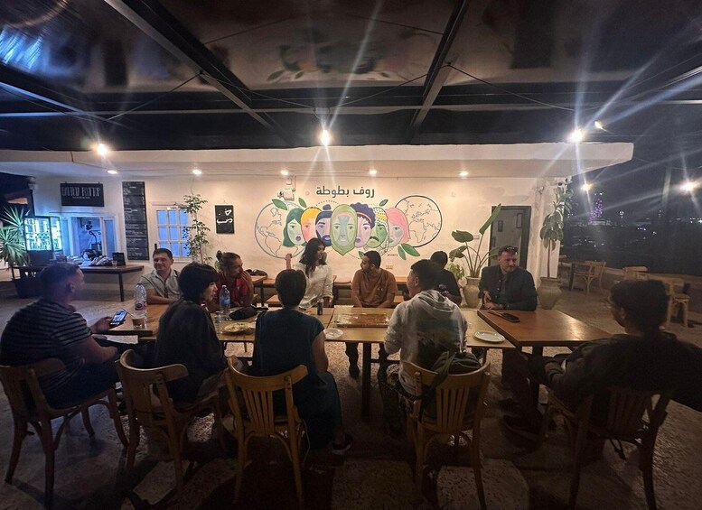 A group of people seated at tables in a cafe with a mural on the wall. 2
