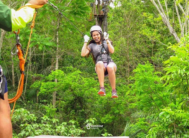 A person suspended on a zipline in a forested area. 1