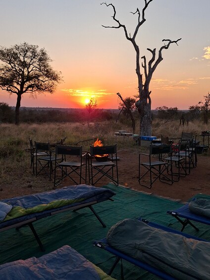 A campsite with tents, chairs, and a fire pit during sunset. 4