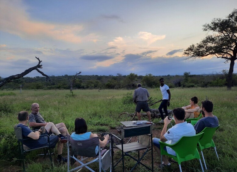 A group of people sitting on chairs outdoors during sunset. 3