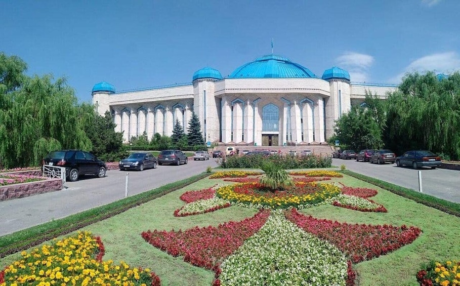 A large building with a blue dome and white columns, surrounded by a well-maintained garden with colorful flower beds. 3