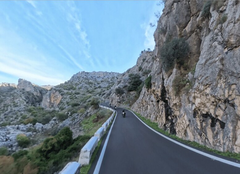 Una carretera de montaña sinuosa con acantilados rocosos a un lado y vegetación escasa al otro. 3